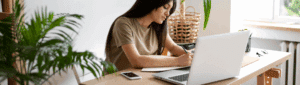 Pagar dívida com desconto: fotografia de uma mulher escrevendo em um papel. À frente está um computador.