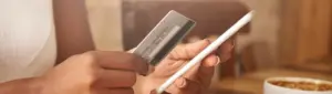 Cartão de crédito negado: fotografia de uma pessoa segurando um cartão de crédito e um celular.
