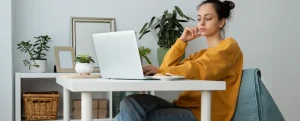 Imposto de renda: fotografia de uma mulher usando o computador em sua casa.