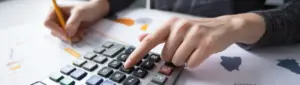 Salário mínimo: fotografia de uma pessoa escrevendo e digitando em uma calculadora.