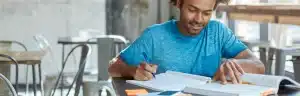 Nome sujo faculdade: fotografia de um homem estudando com livros.