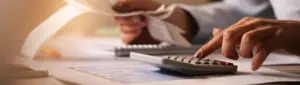 Parcelar dívida ativa: fotografia de uma pessoa digitando em uma calculadora.