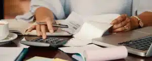 Negociar dívida da Claro: fotografia de uma pessoa digitando em uma calculadora com faturas na mesa.