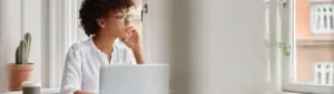 Análise de crédito: fotografia de uma mulher usando o computador e falando ao telefone.
