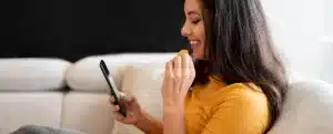 Banco Agibank: fotografia de uma mulher sorrindo enquanto olha para o celular.