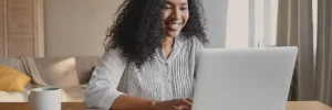 Renegociar banco Pan: fotografia de uma mulher sorridente usando o notebook.