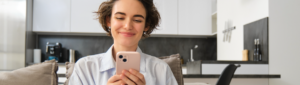 Open Finance: fotografia de uma mulher sorrindo enquanto usa o celular.