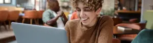 Renegociar FIES: fotografia de uma estudante sorrindo enquanto olha para o computador.