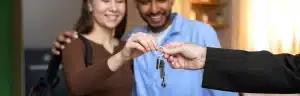 Financiamento nome sujo: fotografia de um casal sorrindo enquanto recebe uma chave de casa.