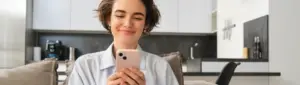 Conta digital Sicredi: fotografia de uma mulher sorrindo enquanto usa o celular.
