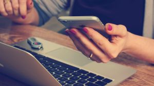 mulher na frente de um notebook e com um smartphone na mão