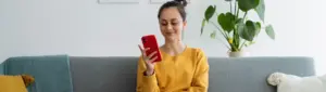 Como aumentar o score: fotografia de uma mulher sorrindo enquanto olha para o celular.