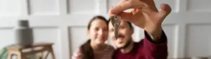 Score para alugar imóvel: fotografia de um casal segurando as chaves de sua casa.