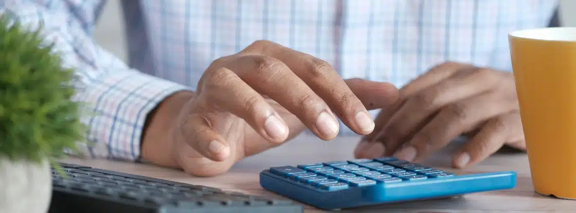 Claro dívidas antigas: fotografia com foco nas mãos de uma pessoa digitando em uma calculadora.