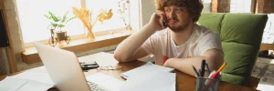 Empresa que limpa nome: fotografia de um homem falando ao telefone enquanto olha para a tela do computador.