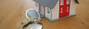 Bens impenhoráveis: fotografia de uma chave com um chaveiro de casa em frente à uma maquete de casa.