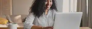 Renner negociar dívida: Fotografia de uma mulher sorrindo enquanto usa o computador.