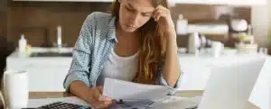 Protesto em cartório: fotografia de uma mulher olhando com expressão de preocupação para um papel.