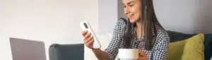 Negociação Magalu: fotografia de uma mulher sorrindo enquanto segura o celular.