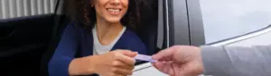 Veículo com dívida ativa pode ser licenciado: fotografia de uma motorista entregando o documento do carro para uma pessoa.