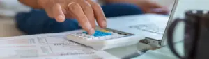 Gestão de dívidas: fotografia de uma pessoa digitando em uma calculadora.