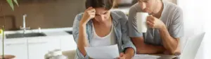 Infidelidade financeira: fotografia de um casal preocupado com contas na mão.