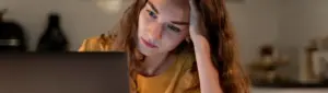 Como pagar INSS desempregado: fotografia de uma mulher com expressão de preocupação olhando para o computador.