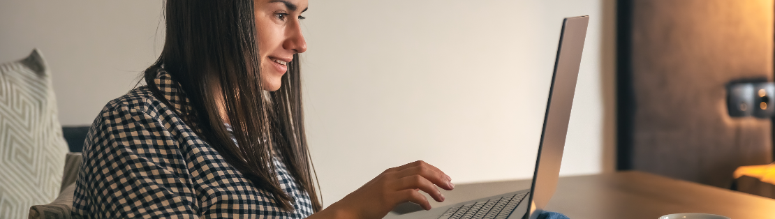 Seguro de vida: fotografia de uma mulher sorrindo e digitando em um notebook.