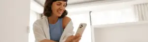Ipanema dívidas: fotografia de uma mulher sorrindo enquanto olha para o celular.