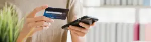 Negociação Riachuelo: fotografia de uma pessoa segurando um cartão de crédito e um celular.