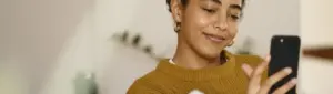 Unopar negociação: fotografia de uma mulher sorrindo enquanto olha para o celular.