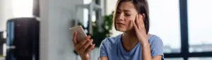 Bloqueio judicial: fotografia de uma mulher olhando com expressão de preocupação para o celular.