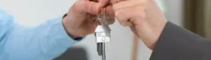 Auxílio Moradia: fotografia de uma pessoa entregando a chave de uma casa para outra pessoa.