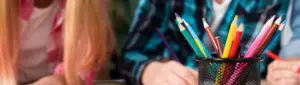Como economizar no material escolar: fotografia de duas crianças com alguns lápis à frente.