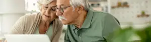 Quanto economizar para aposentadoria: fotografia de um casal de pessoas idosas olhando para o computador.