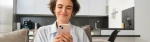 Aplicativo para economizar dinheiro: fotografia de uma mulher sorrindo enquanto olha para o celular.