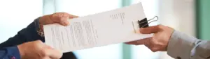 Aviso prévio: fotografia de uma pessoa entregando um documento a outra.
