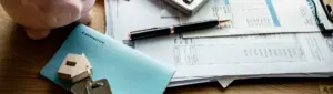 Hipoteca: fotografia com uma chave de casa, alguns documentos e um cofre.