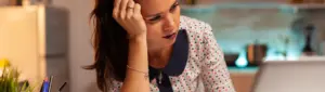 Negocia-DF: fotografia de uma mulher olhando com expressão de preocupação para o computador.