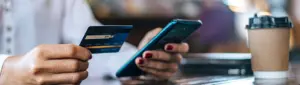 Juros de cartão de crédito: fotografia de uma pessoa segurando um cartão e um celular.