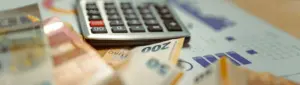 CDB: calculadora e notas de dinheiro sobre uma mesa com gráfico financeiro.