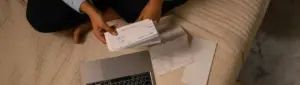 Pessoa conferindo contas e documentos financeiros.