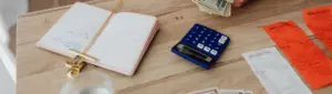 Como sair do vermelho: fotografia de uma mesa com um caderno e calculadora.