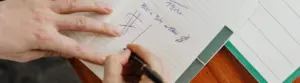 Pessoa anotando gastos do mês no notebook